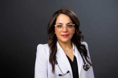 physical therapist hoto wearing lab coat against gray background